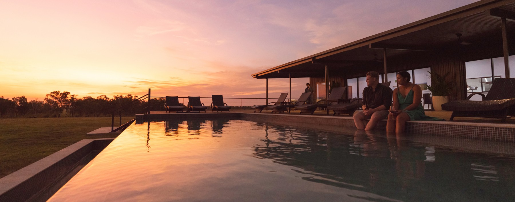 Couple in swimming pool at sunset