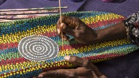 image of womans hand painting a colourful dot painting