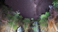 night image of women in waterfalls with stars above