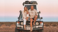 couple sitting on bonnet of 4WD in remote location