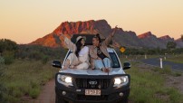 Friends sitting on 4WD bonnet on the side of the road