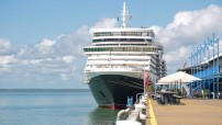 cruise ship docked at wharf with clouds behind