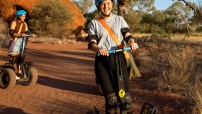 two women riding segways with Uluru in background