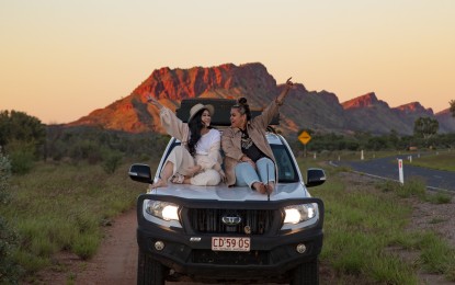 Friends sitting on 4WD bonnet on the side of the road