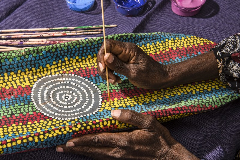 image of womans hand painting a colourful dot painting