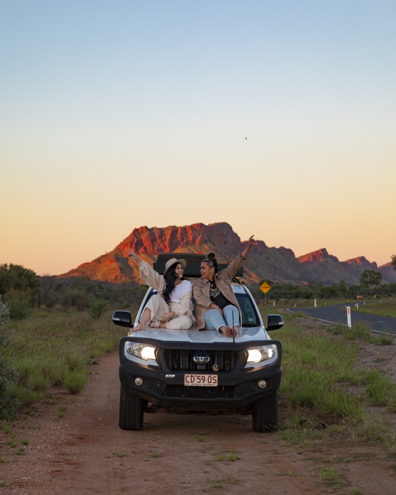 Friends sitting on 4WD bonnet on the side of the road