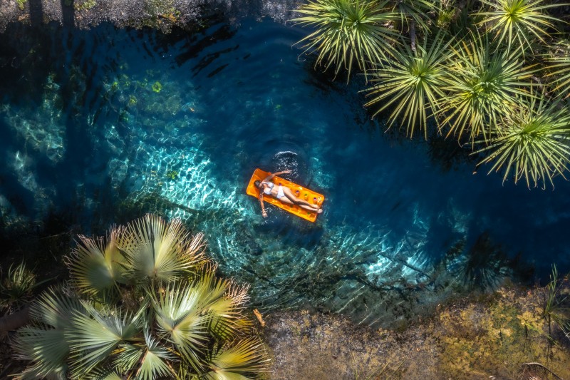 A woman floats on a inflatable bed in Bitter Springs, Elsey National Park