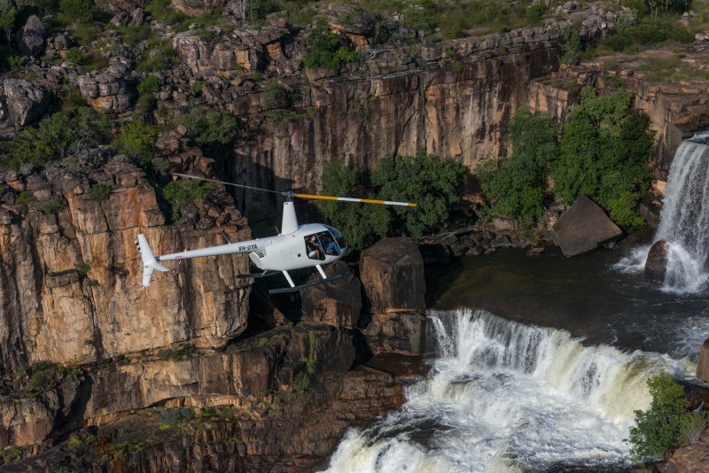 A helicopter flies over Jim Jim falls in Kakadu National Park