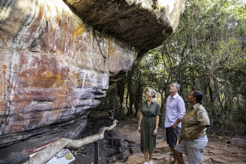 image of three people including Aboriginal guide looking at rock art